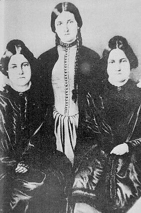 Studio portrait of the three Fox Sisters with the youngest standing between the seated sisters