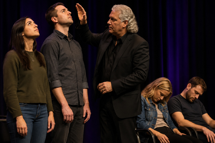 Volunteers focusing on a point during a stage hypnosis exercise while others respond to suggestions.