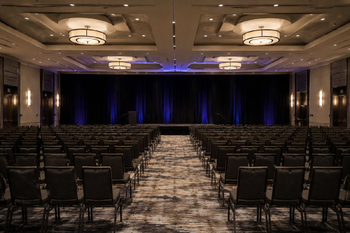 Empty conference room with rows of chairs facing a bare stage, representing audience and venue considerations for a hypnosis show or mentalism show