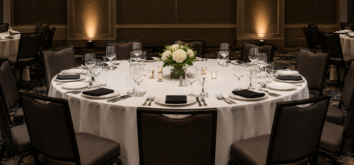 Formally set empty banquet table in a large venue, representing venue planning for entertainment for events