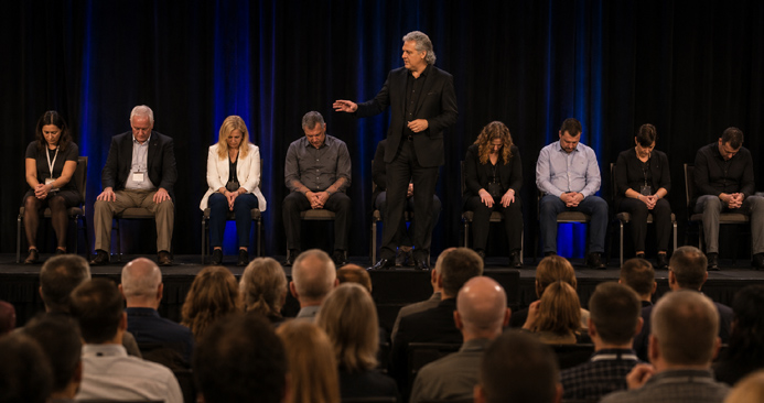 Hypnotist guiding a volunteer into trance while hypnotized on stage in front of a live audience