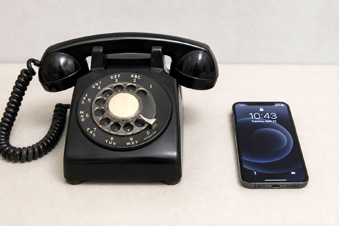 An old rotary telephone next to a modern smartphone represents how technology changes over time