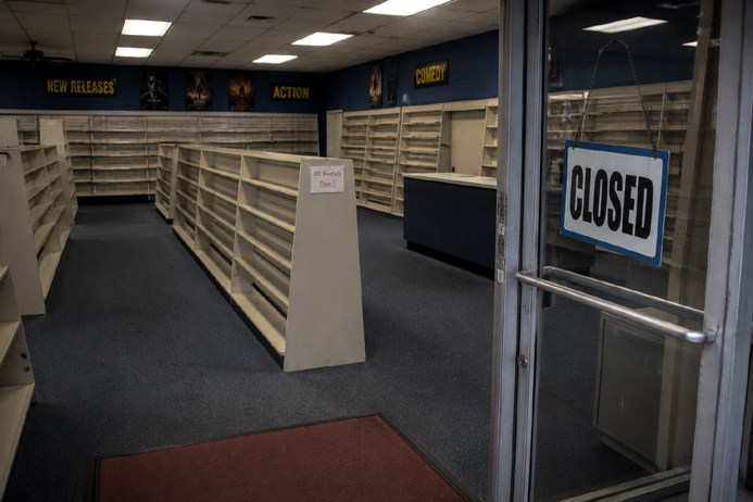 Empty shelves and a closed sign mark the end of a once busy video rental store